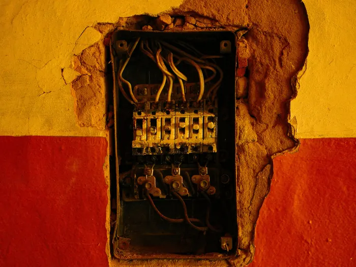 Boîte électrique vétuste encastrée dans un mur fissuré